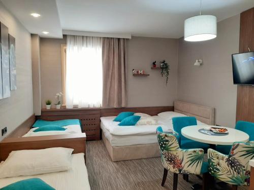 コパオニクにあるSelect Lux Angella-Konaciのベッド2台、テーブルと椅子が備わるホテルルームです。