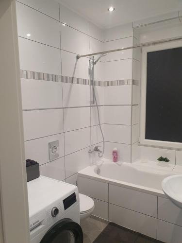 a white bathroom with a toilet and a tub and a sink at Ella's Wolke Appartements - EW5 in Zweibrücken