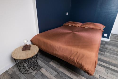 1 cama en un dormitorio con mesa de madera en NUIT BY LIGHT - Dormir Comme A La Maison en Châteaubriant