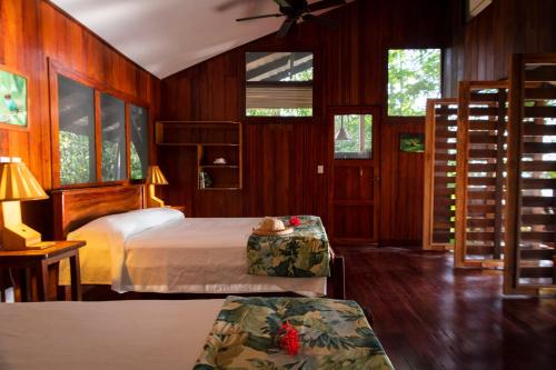 a bedroom with a bed and a table and windows at Tiskita Jungle Lodge in Pavones