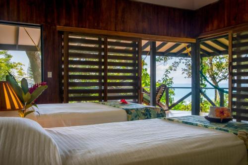 two beds in a room with a view of the ocean at Tiskita Jungle Lodge in Pavones