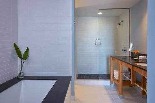 a bathroom with a shower with a counter and a sink at Kimpton Shorebreak Huntington Beach Resort, an IHG Hotel in Huntington Beach