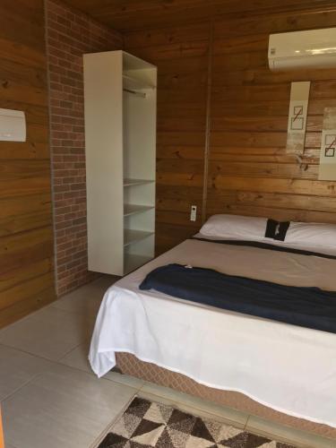 um quarto com uma cama e paredes de madeira em Casa de Madeira em Delfinópolis