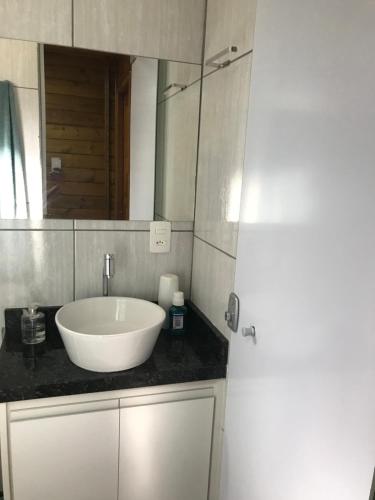 uma casa de banho com um lavatório branco e um espelho. em Casa de Madeira em Delfinópolis
