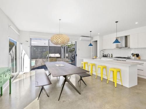 a kitchen with a wooden table and yellow chairs at Lahinch Beach House 32 in Torquay