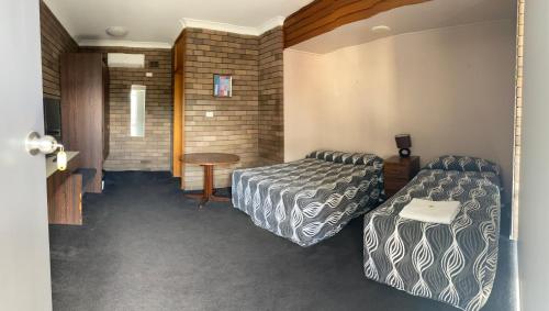 ein Hotelzimmer mit 2 Betten und einem Tisch in der Unterkunft Downtown Motel in Wollongong