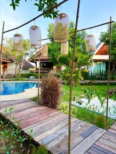 a wooden walkway leading to a house with a pool at Siri Lagoona Resort in Nong Prue