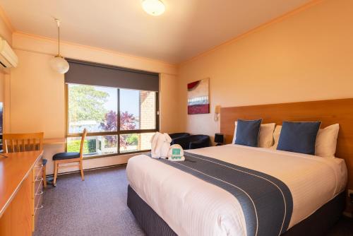 a hotel room with a large bed and a window at Midlands Motel in Taree