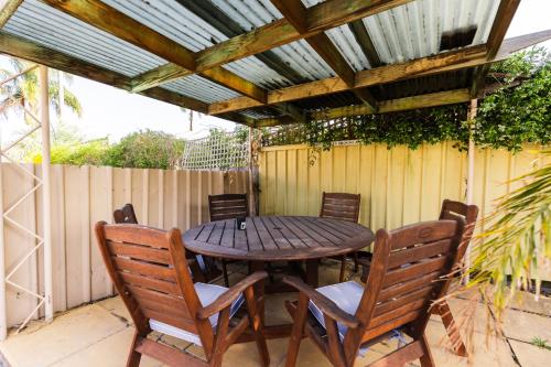 a wooden table and chairs under a wooden pergola at Midlands Motel in Taree