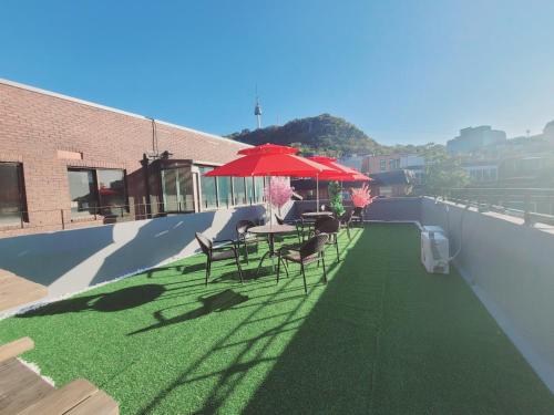 a patio with a table and chairs and a red umbrella at Olive Hostel MyeongDong in Seoul