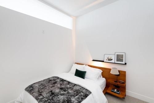 een witte slaapkamer met een bed en een nachtkastje bij Flexhome Skywalk to Fiserv 1BR Apt U1 - READ INFO in Milwaukee