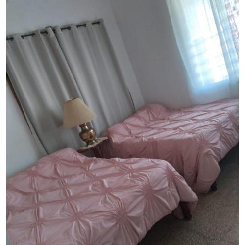 two beds in a room with pink sheets and a lamp at Belretiro Cottage in Bel Retiro