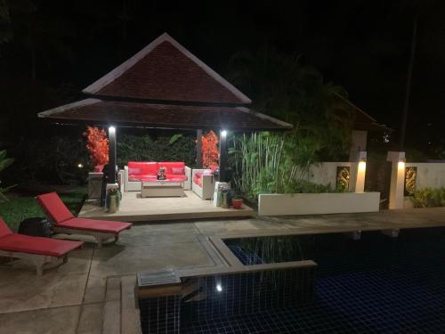 a backyard with a red couch and a pool at night at Samui Dreams Seaview Villa - Bangrak Beach - with Private Pool in Koh Samui 