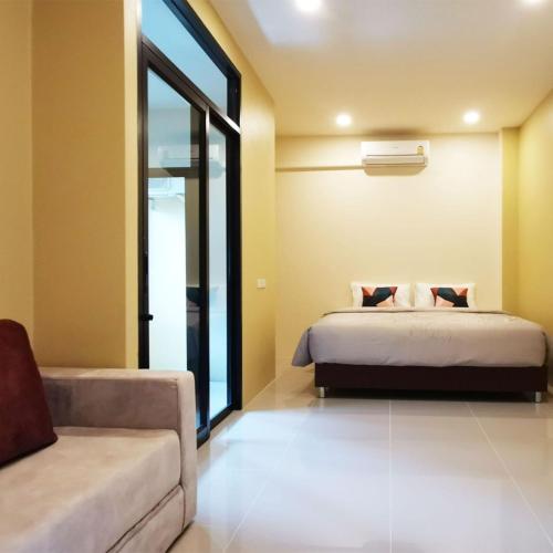 a bedroom with a bed and a couch at The Middle Town SHA in Chiang Rai
