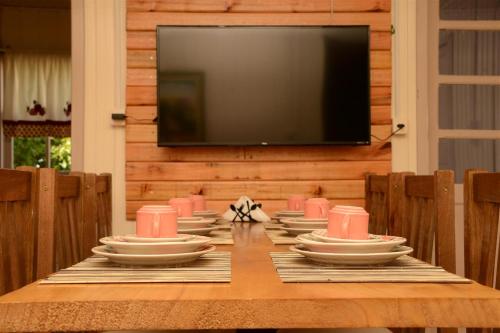 a dining room table with plates and a television at Quintal das Araucárias hospedagem in São Joaquim