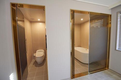 a bathroom with a shower and a toilet and a sink at Denbasta Hotel in Busan