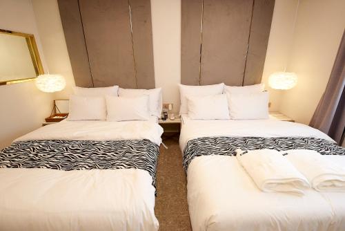 two beds in a hotel room with white sheets at Denbasta Hotel in Busan