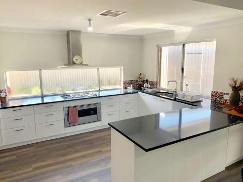 a kitchen with white cabinets and a black counter top at Tranquil Waters in Busselton