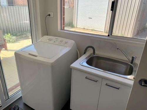 a small kitchen with a sink and a washing machine at Tranquil Waters in Busselton