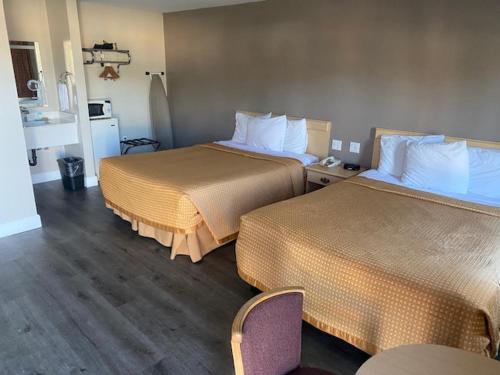 a hotel room with two beds and a chair at North Bay Inn Santa Rosa in Santa Rosa