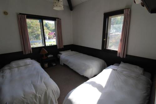 a bedroom with two beds and two windows at Stella八ヶ岳原村-星空,サウナ,BBQ,大型スクリーンを楽しめる八ヶ岳の貸切宿 in Hara