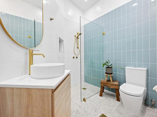 un bagno con lavandino, WC e specchio di Yabbarra Beach House a Dalmeny