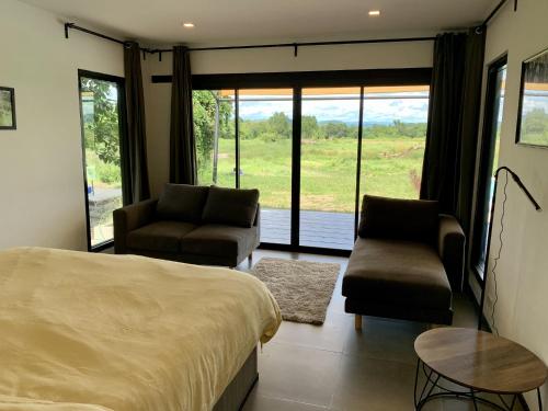a bedroom with a bed and a couch and chairs at I love phants Lodge in Ban Huai Thawai
