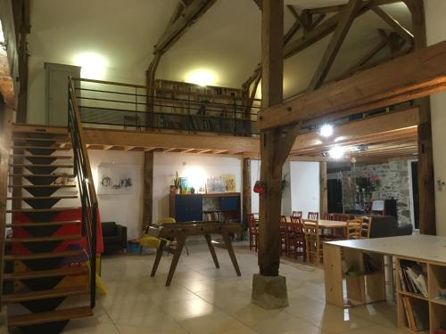 a room with a loft with a table and chairs at Grange de la Menagerie in Mouilleron-le-Captif