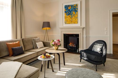 a living room with a couch and a fireplace at Steigenberger Icon Parkhotel Düsseldorf in Düsseldorf