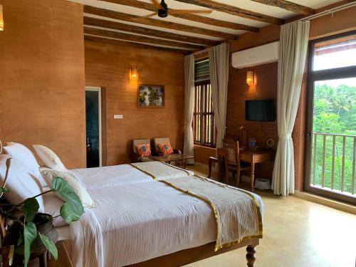 a bedroom with a bed and a table and a window at AMARA AYURVEDA RETREAT- Overlooking Evergreen Western Ghats an ecologically sustainable living space in Kovalam in Kovalam