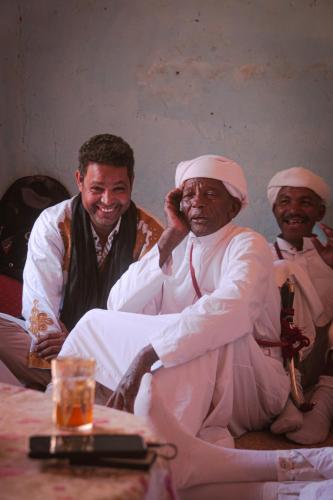 a group of three men sitting next to a table at Bivouac Joudour Sahara in Mhamid