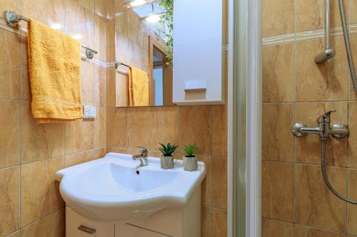 y baño con lavabo blanco y ducha. en Apartments Alen, en Fažana