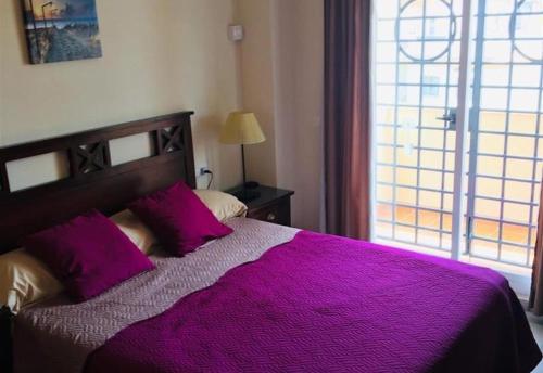 sypialnia z dużym fioletowym łóżkiem i oknem w obiekcie Lux Apartm Beauvivir w mieście Torre del Mar