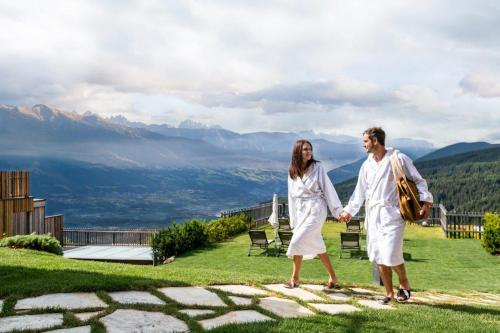 a man and woman holding hands while walking on a mountain at Tratterhof Mountain Sky Hotel in Maranza