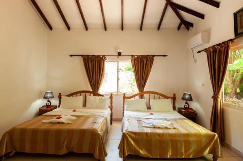 a bedroom with two beds and a window at Villa Veuve Casadani Hotel in La Digue