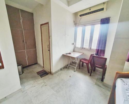a room with a desk and a table and chairs at Georgian Inn in Kolkata