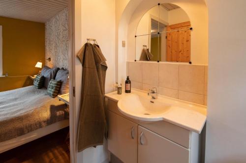 a bathroom with a sink and a bed and a mirror at GÆSTEHUSET in Tarm