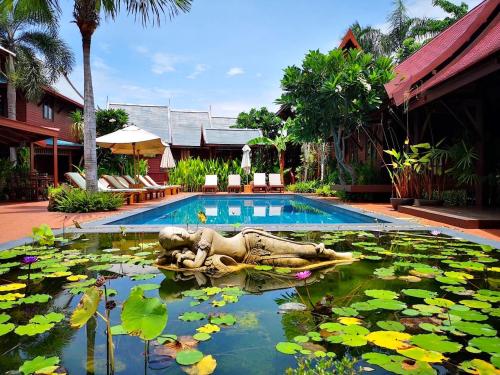 a pool with a statue in the water with lilies at Ruenkanok Thaihouse Resort in Hua Hin