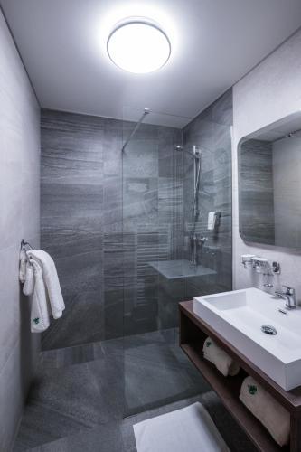 a bathroom with a sink and a glass shower at Hotel Concertino Zlatá Husa in Jindrichuv Hradec