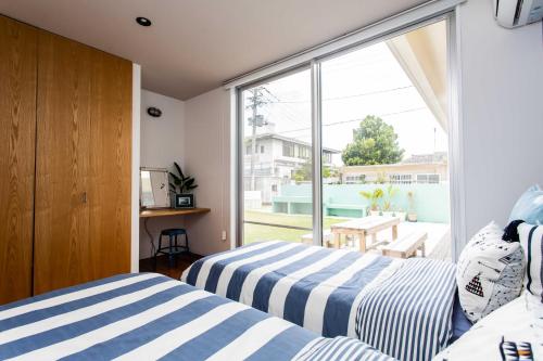 2 camas en una habitación con ventana en Hotel Yanbarunia en Nago