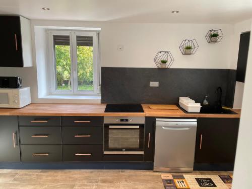 une cuisine avec des placards noirs et blancs et une fenêtre dans l'établissement Maison de campagne proche Lac de Bouzey, à Chaumousey