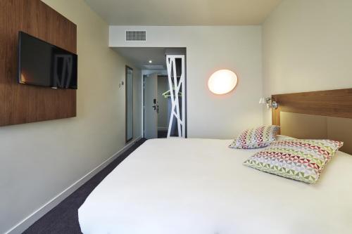 a bedroom with a bed and a flat screen tv at Campanile Paris Sud Saclay- Gif sur yvette in Saclay