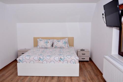 a bedroom with a white bed and a flat screen tv at La Miruna in Comăneşti