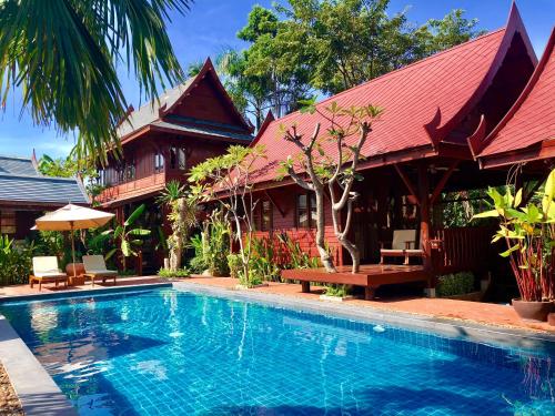 a swimming pool in front of a house at Ruenkanok Thaihouse Resort in Hua Hin