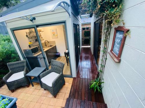 een patio met 2 stoelen en een deur naar een keuken bij River cottage in Blairgowrie