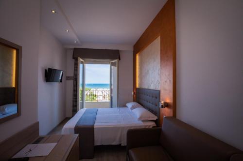 a bedroom with a bed and a couch and a window at Hotel Gabbiano in Rimini