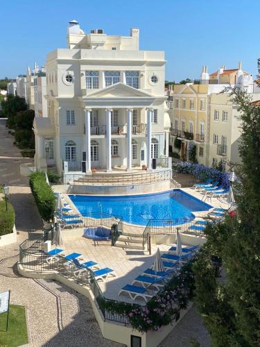 una grande casa bianca con piscina e sedie di Old Village a Vilamoura