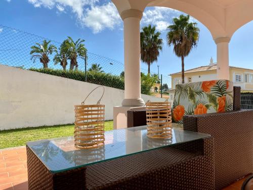 a glass table and chairs on a patio with palm trees at Villa Med - private pool, garden, sun all day, stunning views in Albufeira