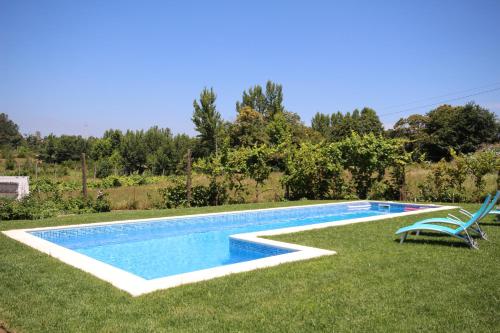 a swimming pool with two chairs in the grass at B&B Villa Branca Barreiros AL98139 in Barreiros