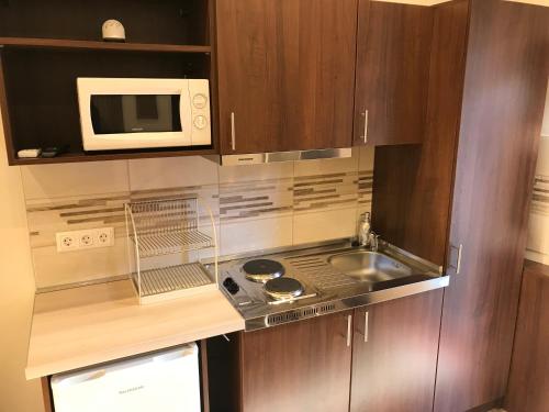 a small kitchen with a sink and a microwave at Termál Apartmanház in Veresegyház